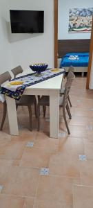 a white table with chairs and a table with a bowl on it at La Casa sulla Piazza in Sciacca