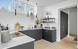 uma cozinha com armários pretos e bancadas brancas em Cozy Home In Aakirkeby With Kitchen em Vester Sømarken