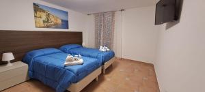 a bedroom with two blue beds with shoes on them at La Casa sulla Piazza in Sciacca