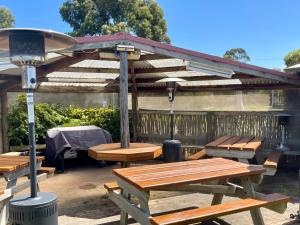 a group of picnic tables under a wooden pergola at Swansea Cottages & Lodge Suites in Swansea