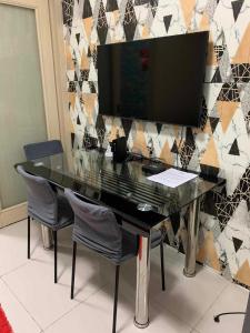 a glass table with chairs and a television on a wall at Stay Cay Affordable Price by -Mang Domeng in Manila