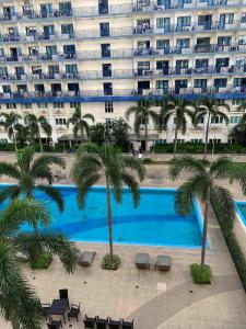 a large apartment building with a swimming pool and palm trees at Stay Cay Affordable Price by -Mang Domeng in Manila