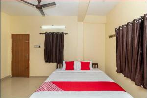 a bedroom with a large bed with red pillows at OYO Thirumal Residency in Tirunelveli