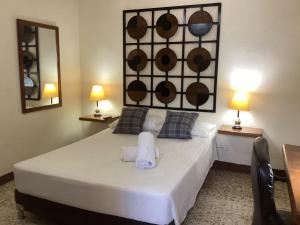 メデジンにあるManila Su Casaのベッドルーム1室(白いベッド1台、テーブル2台、ランプ2つ付)