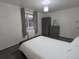 a white bedroom with a large bed and a window at 3 Bedroom Apartment Sleeps 8 in Edinburgh