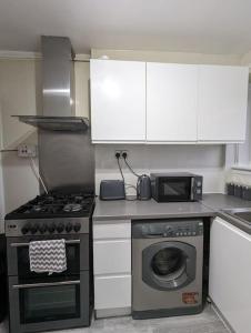 eine Küche mit einem Herd und einer Mikrowelle in der Unterkunft 3 Bedroom Apartment Sleeps 8 in Edinburgh