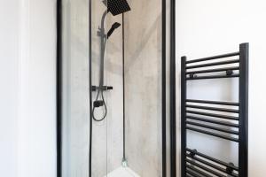 a shower in a bathroom with a glass door at Aviary Nest by Nordstay in Amley