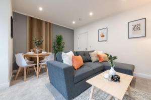 a living room with a blue couch and a table at Aviary Nest by Nordstay in Amley