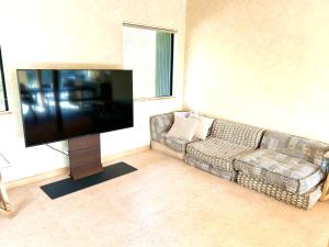 sala de estar con sofá y TV de pantalla plana en くろまま, en Oshima