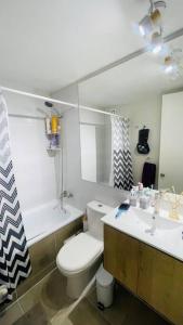 a bathroom with a toilet and a sink and a mirror at Departamento completo a pasos del mar in La Serena