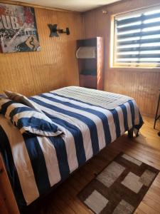 1 dormitorio con 1 cama con manta de rayas azul y blanco en Ruta Austral - Coyhaique, en Coyhaique