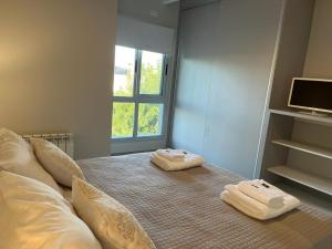 a bedroom with two towels on a bed with a window at Departamento Complejo Los Agaves - Chacras de Coria in Ciudad Lujan de Cuyo