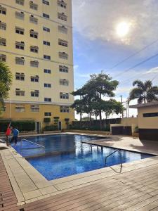 a swimming pool in front of a tall building at Mados Serene Condo with Southwoods Skyline View in Biñan