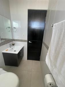 Habitación con baño privado en un piso 24 con todo lo necesario في مدينة باناما: حمام مع مرحاض وباب أسود