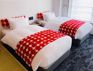 two beds with red and white covers in a room at Tabist kiki HOTEL KYOTO Sanjo Takakura in Kyoto