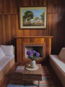um quarto com lareira e um vaso de flores roxas em La Fontana Cabaña - Oxapampa em Oxapampa