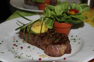 a piece of steak on a plate with a potted plant at Parkhotel Framke in Ehlscheid