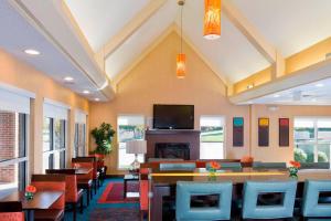 a restaurant with chairs and tables and a tv at Residence Inn Madison East in Madison