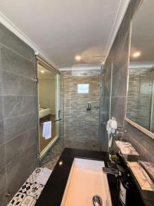 a bathroom with a shower and a sink and a tub at Kaloka Airport Hotel in Labu Sumbawa