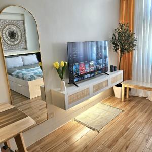 uma sala de estar com uma televisão de ecrã plano e um espelho em Mados Serene Condo with Southwoods Skyline View em Biñan