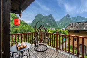 a chair on a deck with mountains in the background at Yangshuo Ancient Garden Boutique Hotel in Yangshuo