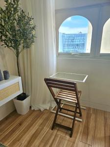 uma cadeira num quarto com uma janela e uma árvore em Mados Serene Condo with Southwoods Skyline View em Biñan