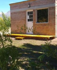 a small house with a white door and a yard at Ushua Aike (Nuestro Lugar) in Los Antiguos