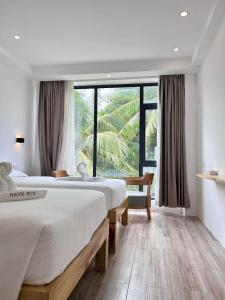 a bedroom with two beds and a large window at Fun Hotel in Panglao