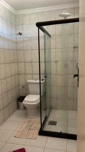 y baño con aseo y cabina de ducha de cristal. en Condomínio Parque de jacuipe, en Camaçari