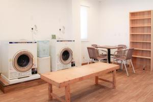 een kamer met wasmachines en een tafel en stoelen bij Hostel Wasabi Asakusa in Tokyo