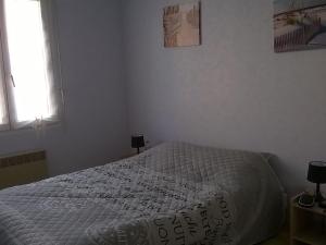 um quarto com uma cama com um edredão branco em Maison L'Aiguillon-sur-Mer, 3 pièces, 5 personnes - FR-1-476-42 em LʼAiguillon-sur-Mer