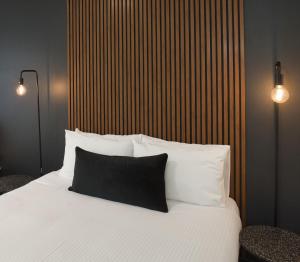 una camera da letto con un letto bianco e un cuscino nero di Echo Point Discovery Motel a Katoomba