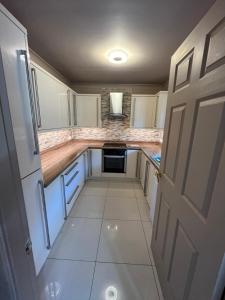 una pequeña cocina con armarios blancos y una puerta en Retreat at The Knowe Auchincruive Estate, en Ayr