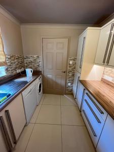 a small kitchen with white appliances and a door at Retreat at The Knowe Auchincruive Estate in Ayr