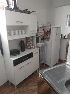 Una cocina con gabinetes blancos y un refrigerador. en APÊ AVENIDA - BONITO/PE, en Bonito