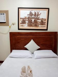 a bed with white sheets and a picture on the wall at Mariella's Guest House in Siquijor