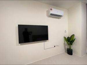 einen Flachbild-TV, der an einer weißen Wand hängt in der Unterkunft J&SM Riverine resort homestay in Kuching