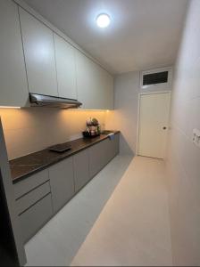 J&SM Riverine resort homestay في كوتشينغ: مطبخ بدولاب بيضاء وأرضية بيضاء