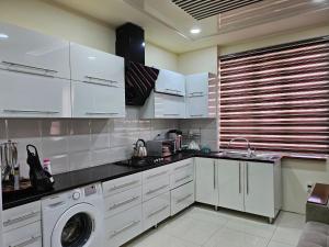 cocina con armarios blancos y lavadora en Аппартаменты Rohat, en Samarkand