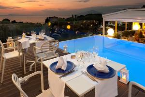 a restaurant with white tables and chairs on a balcony at Hotel Rivage in Sorrento