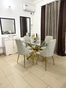 comedor con mesa de cristal y sillas blancas en Ulili 1br apts Makepe, en Douala