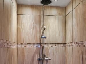 a shower in a bathroom with wooden walls at Beech Cottage in Carnforth