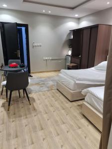 1 dormitorio con 2 camas, escritorio y mesa en بيت الجود للأجنحة المفروشة, en Sīdī Ḩamzah