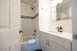 a white bathroom with a sink and a mirror at Bright Pacifica Townhouse in Pacifica +7 photos