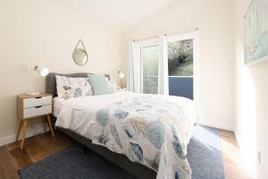 a white bedroom with a bed and a window at Bright Pacifica Townhouse in Pacifica