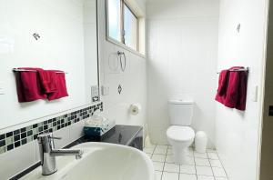 a white bathroom with a sink and a toilet at Motel Myall in Dalby