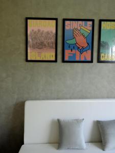 four framed pictures on a wall above a white couch at Single Fin Siargao in General Luna