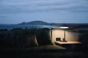 a building with a bench in the middle of a field at Mount View Marrawah in Marrawah