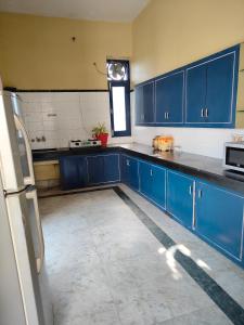 une grande cuisine avec des placards bleus et une fenêtre dans l'établissement Shantiniketan 2 BHK Homestay in Ayodhya, à Ayodhya