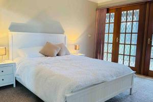 1 dormitorio con 1 cama blanca grande y 2 lámparas en Dhanda Farm Bathurst, en Raglan